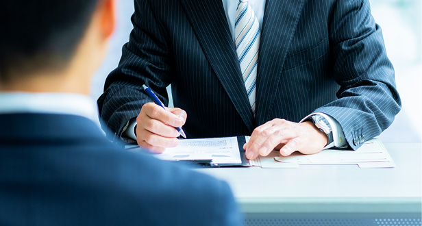 スーツ姿の男性が面談中に書類へ記入している様子