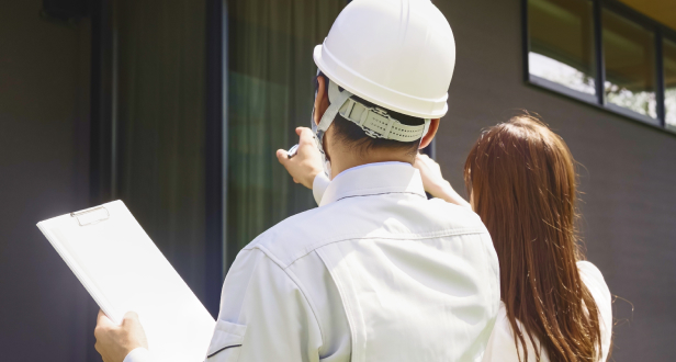 ヘルメットをかぶった作業員が建物を現地チェックしている様子